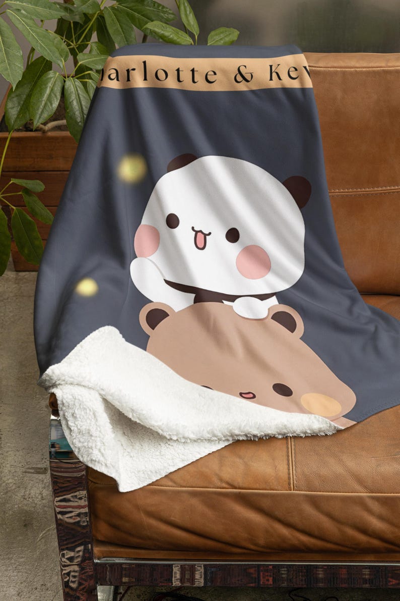 Pu&ograve; includere: Una morbida e soffice coperta con uno sfondo blu scuro che presenta un panda bianco con guance rosa e un orso marrone con un naso marrone chiaro. La coperta &egrave; foderata in sherpa bianco e ha una striscia marrone con il testo "Charlotte & Kev".