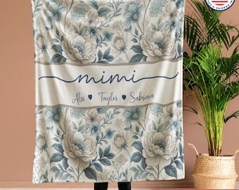 May include: A floral blanket in blue, grey, and white. The blanket has the name "mimi" in cursive, with the names Alex, Taylor, and Sabrina below. The blanket is printed in the USA.