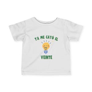 May include: White baby t-shirt with a green and blue graphic. The graphic features a smiling yellow lightbulb with the text "YA ME CAYÓ EL VEINTE" in green above and below the lightbulb.