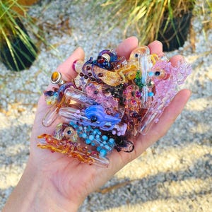 May include: A collection of small, handcrafted glass pipes featuring intricate octopus designs in various colors including pink, blue, orange, and purple. Each piece displays detailed tentacles and glass eyes, showcasing a variety of translucent and opaque glass textures.