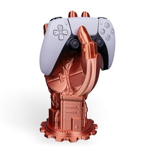 Könnte beinhalten: Eine kupferfarbene Roboterhand hält einen weißen und schwarzen Videospielcontroller. Die Hand ist an einer Zahnrad-förmigen Basis befestigt.