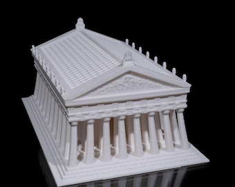 May include: A white 3D printed model of a Greek temple with a detailed roof and columns. The model is sitting on a black surface and is reflecting light.