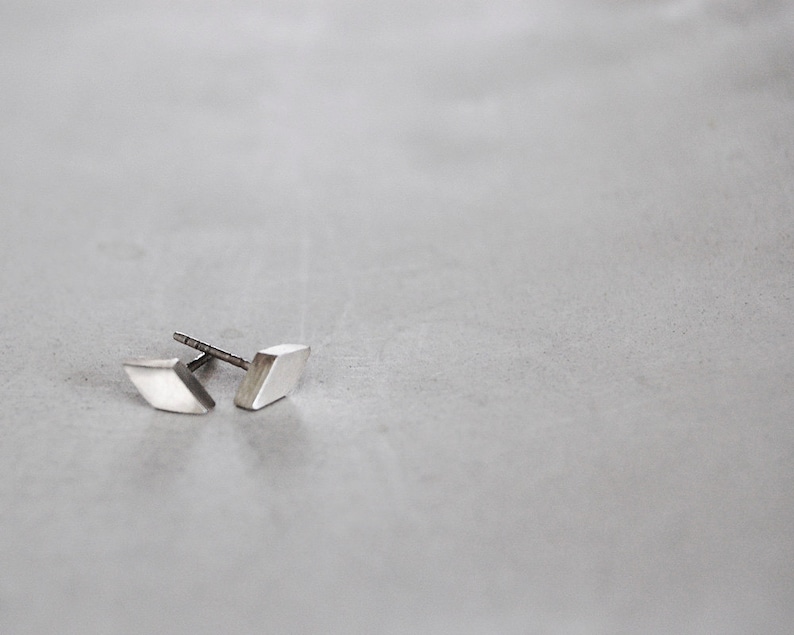 May include: A pair of silver diamond-shaped earrings.