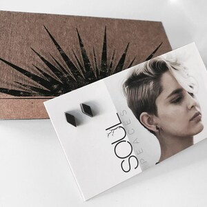 May include: A pair of black diamond-shaped earrings in a small white box with the text "SOUL PEACES" printed on it.