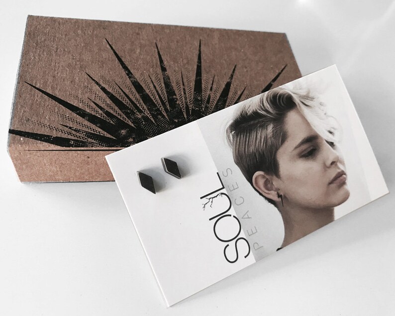 May include: A pair of black diamond-shaped earrings in a small white box with the text "SOUL PEACES" printed on it.