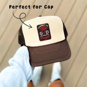 Puede incluir: Gorra de camionero marrón y beige con parte trasera de malla y visera curva. La gorra presenta un parche con las palabras "CONNECT TO GOD" y "THE PASSWORD IS: Prayer". Un accesorio de moda.