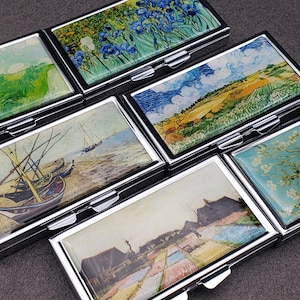 Könnte beinhalten: Sechs kleine silberne Pillendosen mit verschiedenen berühmten Gemälden auf den Deckeln. Die Gemälde zeigen ein Blumenfeld, eine Landschaft mit einem Fluss, ein Blumenfeld, eine Seestück mit Booten, ein Blumenfeld und ein Blumenfeld.