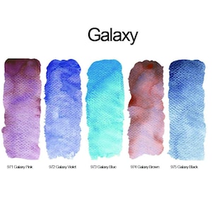 Może przedstawiać: Pięć pionowych pr&oacute;bek akwareli z etykietą Galaxy. Kolory to 971 Galaxy Pink, 972 Galaxy Violet, 973 Galaxy Blue, 974 Galaxy Brown oraz 975 Galaxy Black. Każda pr&oacute;bka przedstawia teksturowaną, p&oacute;łprzezroczystą aplikację farby na papierze.