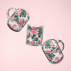Pode incluir: Três canecas de vidro com estampa floral tropical com flores rosa e folhas verdes. As canecas estão em posições diferentes, uma caneca está direita e duas canecas estão inclinadas.