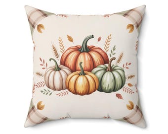 May include: Square throw pillow featuring a watercolor illustration of pumpkins in shades of orange, yellow, and green. The pillow has a cream-colored background with fall foliage and a plaid border in beige and green.