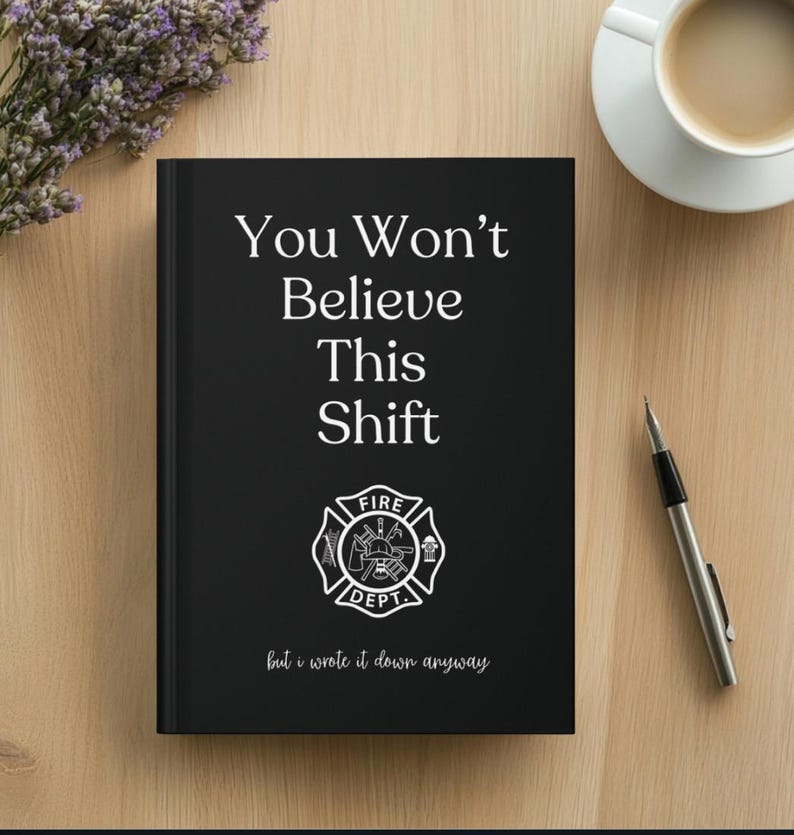May include: A black notebook with the text "You Won't Believe This Shift" and a fire department emblem. The notebook also has the text "but I wrote it down anyway". A pen and a cup of coffee are next to the notebook.