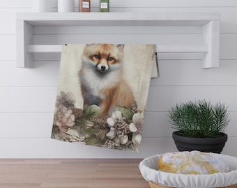 Puede incluir: Una toalla de cocina decorativa con una ilustración de acuarela de un zorro rodeado de flores. El zorro tiene pelaje naranja y blanco, con una cara detallada. Las flores son en tonos de blanco, gris y verde.