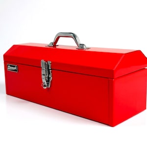 May include: A bright red metal toolbox with a silver handle and latch. The rectangular box has a hinged lid and a small rectangular label on the side. The toolbox is designed for storing tools and hardware.
