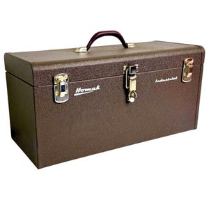 May include: A brown metal toolbox with a textured finish, featuring a dark handle and silver-colored metal latches. The front of the box displays the white text Homak and Industrial. The rectangular container has a hinged lid and a secure locking mechanism.