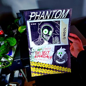 Pode incluir: Um cartaz retangular com a palavra PHANTOM no topo. Exibe um personagem de desenho animado com olhos verdes e peito esquelético, uma etiqueta GHOUL e o texto DO NOT APPROACH e I'M GOING GHOST. Uma faixa amarela ECTOPLASM está na parte inferior.