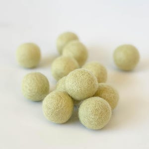 May include: A group of light green felt balls. The balls are soft and fuzzy, and they are perfect for crafts or decorations.