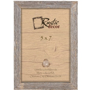 May include: A rustic wood picture frame with a light grey finish. The frame is 5x7 inches and has the text "Rustic decor" printed on the front. The back of the frame has the text "100% Recycled Materials Made in the USA Oklahoma City, Oklahoma 73179".