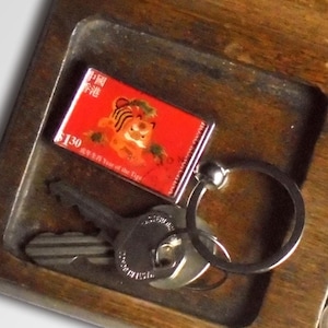 May include: A wooden tray with a key holder, a keychain with a red Chinese New Year stamp featuring a tiger, and a compartment with US coins. The stamp reads "5130 Year of the Tiger".