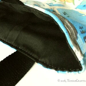 May include: A black fabric bag with a blue and white patterned lining. The bag has a black strap and is made of a soft, durable material.