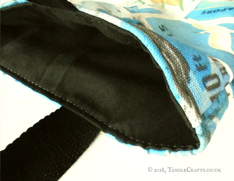 May include: A black fabric bag with a blue and white patterned lining. The bag has a black strap and is made of a soft, durable material.