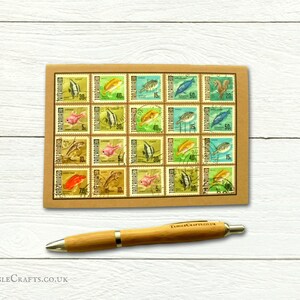 May include: A sheet of vintage Tanzanian postage stamps featuring colourful illustrations of fish. The stamps are arranged in a grid pattern on a brown paper background. The stamps are all different denominations, ranging from 5 to 50 cents.