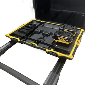 Może przedstawiać: Czarna i żółta skrzynka narzędziowa z wysuwaną tacą. Taca mieści dwa czarno-żółte akumulatory 20V. Skrzynka ma czarne wnętrze i żółtą ramę. Skrzynka jest otwarta i gotowa do użycia.