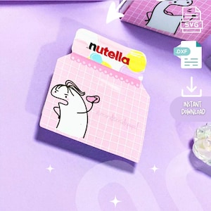 Puede incluir: Una plantilla de embalaje imprimible rosa y blanca para un tarro de Nutella. La plantilla presenta un personaje de dibujos animados sosteniendo un tarro de Nutella y la palabra "nutella" en letras rojas. La plantilla está etiquetada como "REF: PACK001 NUTELLA".