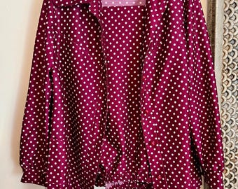 May include: A burgundy polka dot button-up shirt with long sleeves and a collared neckline.