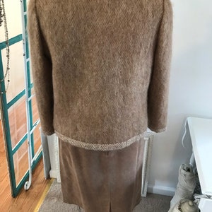 May include: A brown fuzzy sweater with a tweed trim and a brown suede skirt.