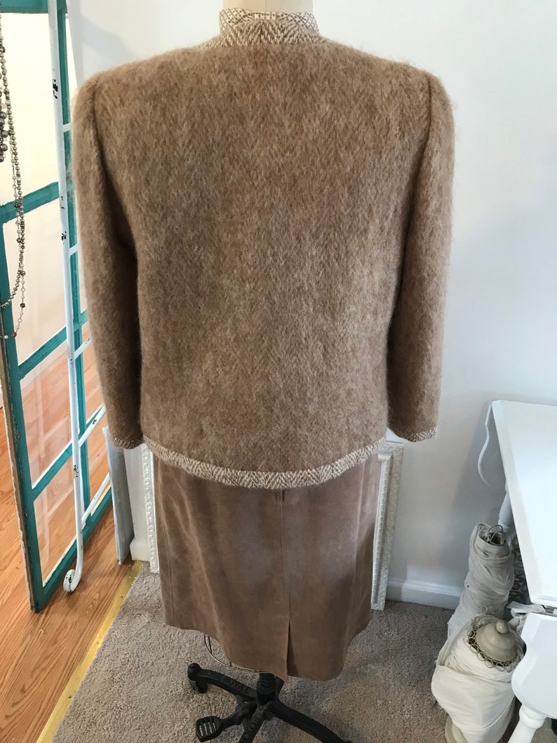 May include: A brown fuzzy sweater with a tweed trim and a brown suede skirt.