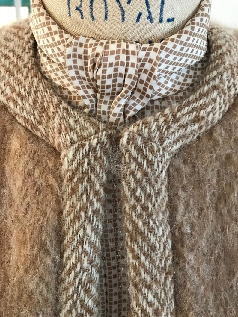 May include: A brown and white fuzzy sweater with a brown and white checkered scarf tied around the neck.