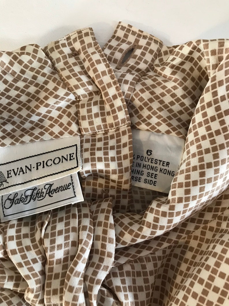 May include: A white and brown checkered blouse with a brown collar and a label that reads "Evan-Picone Saks Fifth Avenue" and "6 Polyester Made in Hong Kong Hing See Reverse Side".