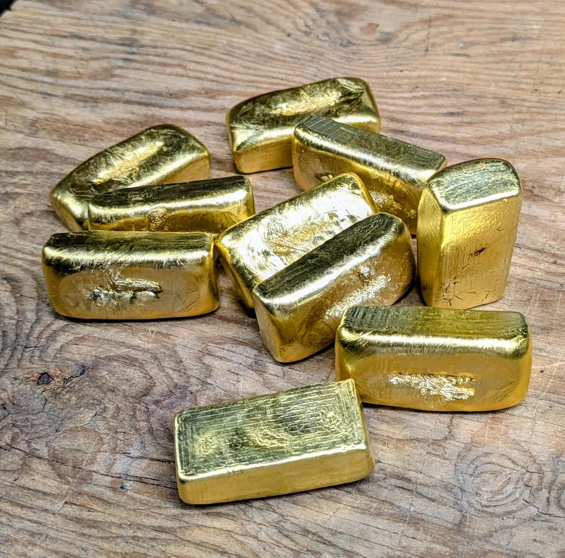 May include: A collection of gold bars, each with a rectangular shape and a shiny, reflective surface. The bars are arranged on a wooden surface, creating a display of wealth and value. The gold bars are a symbol of investment and financial security.