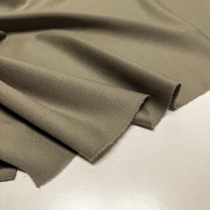 Discover a high-quality Merino Wool in sage color (olive) with a touch of Cashmere thread. This Fabric is ideal for suits, trousers. Merino Wool is a luxurious fabric, made with cashmere fibers, extremely soft and comfortable to wear. This fabric lends a sophisticated look and style to the items made from it.