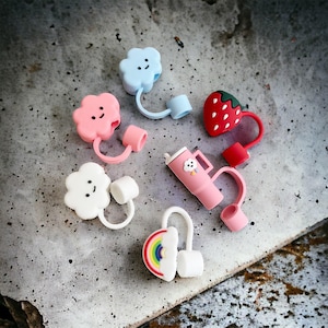 May include: A set of six colourful silicone bottle stoppers with different designs, including a strawberry, a cloud, and a rainbow. The stoppers are designed to fit standard-sized bottles.