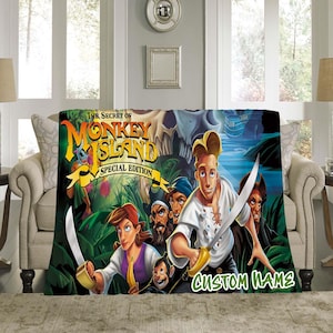 Könnte beinhalten: Eine weiche Decke mit Kunstwerken aus "The Secret of Monkey Island: Special Edition". Das Design zeigt Charaktere mit Schwertern, einen Schädel und den Text "CUSTOM NAME". Die Decke ist über einem beigen Sofa drapiert.