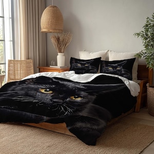 May include: Black cat bedding set featuring a close-up of a black cat with yellow eyes. The set includes a duvet cover and two pillowcases. The bedding is on a wooden bed frame with a neutral-colored rug.