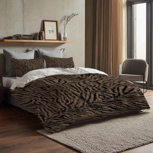May include: A bed with a brown and black zebra-striped comforter and matching pillowcases. The bed is made with white sheets and gray pillowcases. The room has a neutral color scheme with a gray rug and curtains.