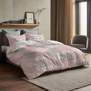 Pode incluir: Uma cama com um edredom estampado e um conjunto de almofadas. O edredom apresenta um design de patchwork em tons de rosa, cinza e branco. A cama é feita com almofadas cinzentas e um lençol branco. O quarto tem um esquema de cores neutras.