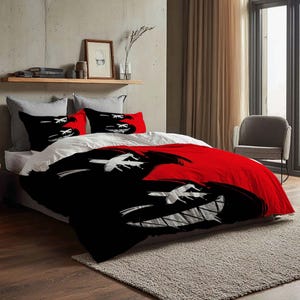 May include: A bed with a red and black comforter set featuring a graphic design of a grinning face. The set includes two pillowcases with the same design. The bed is made up with white sheets and gray pillows.