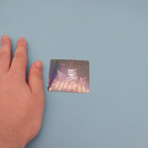 以下が含まれることがあります： 「I.T. Department」というテキストが書かれた、ピンクの猫がラップトップに座っているホログラフィックステッカーです。