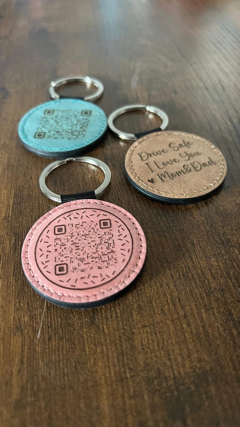 Puede incluir: Llaveros redondos de cuero en rosa, azul y marr&oacute;n. Algunos tienen c&oacute;digos QR, otros el mensaje "Drive Safe I Love You Mom & Dad". Cada llavero tiene un llavero plateado.