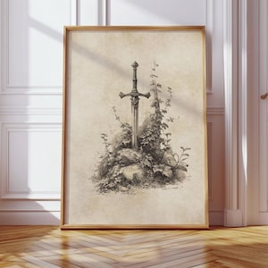 Peut inclure: Illustration encadr&eacute;e d'une &eacute;p&eacute;e plant&eacute;e dans une pierre, entour&eacute;e de feuillage, en nuances de gris. L'&oelig;uvre d'art a un style vintage. Le cadre en bois clair renforce l'aspect classique et intemporel de l'image.