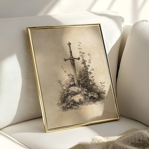 Peut inclure: Une impression encadr&eacute;e repr&eacute;sentant une &eacute;p&eacute;e plant&eacute;e dans une pierre, entour&eacute;e de verdure, dans des tons s&eacute;pia. Le cadre est dor&eacute;. L'illustration &eacute;voque un th&egrave;me m&eacute;di&eacute;val et fantastique, avec des d&eacute;tails fins.