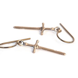 May include: A pair of gold-toned sword earrings with a simple hook design.