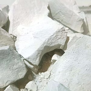 May include: A close-up of a pile of white chalk rocks. The rocks are irregular in shape and have a rough texture.