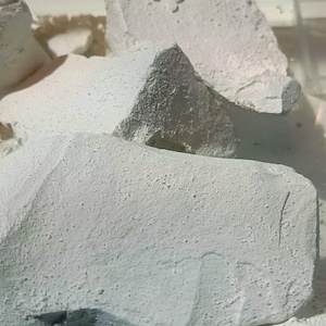 以下が含まれることがあります： 白いチョークの岩の積み重ねのクローズアップ。岩はざらざらしていて質感があり、いくつかは摩耗の跡が見られます。
