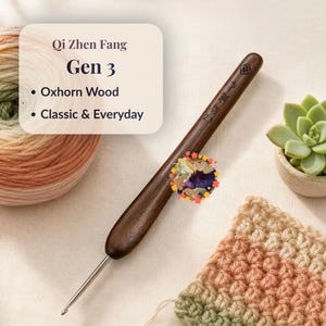 May include: A dark brown oxhorn wood crochet hook with a metal tip, featuring the text Qi Zhen Fang Gen 3, Oxhorn Wood, and Classic & Everyday. The handle is engraved with a floral symbol and the number 2.3, positioned near a ball of yarn.