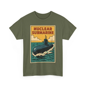 May include: Olive green t-shirt featuring a retro-style graphic of a black submarine on teal water, with the words "NUCLEAR SUBMARINE" in a yellow and red rectangular frame. The design evokes a vintage aesthetic.