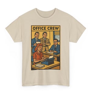 May include: Beige t-shirt with a vintage-style office scene illustration. The design shows a woman using a typewriter and three men. The words "OFFICE CREW" are displayed at the top of the graphic in a rectangular box.